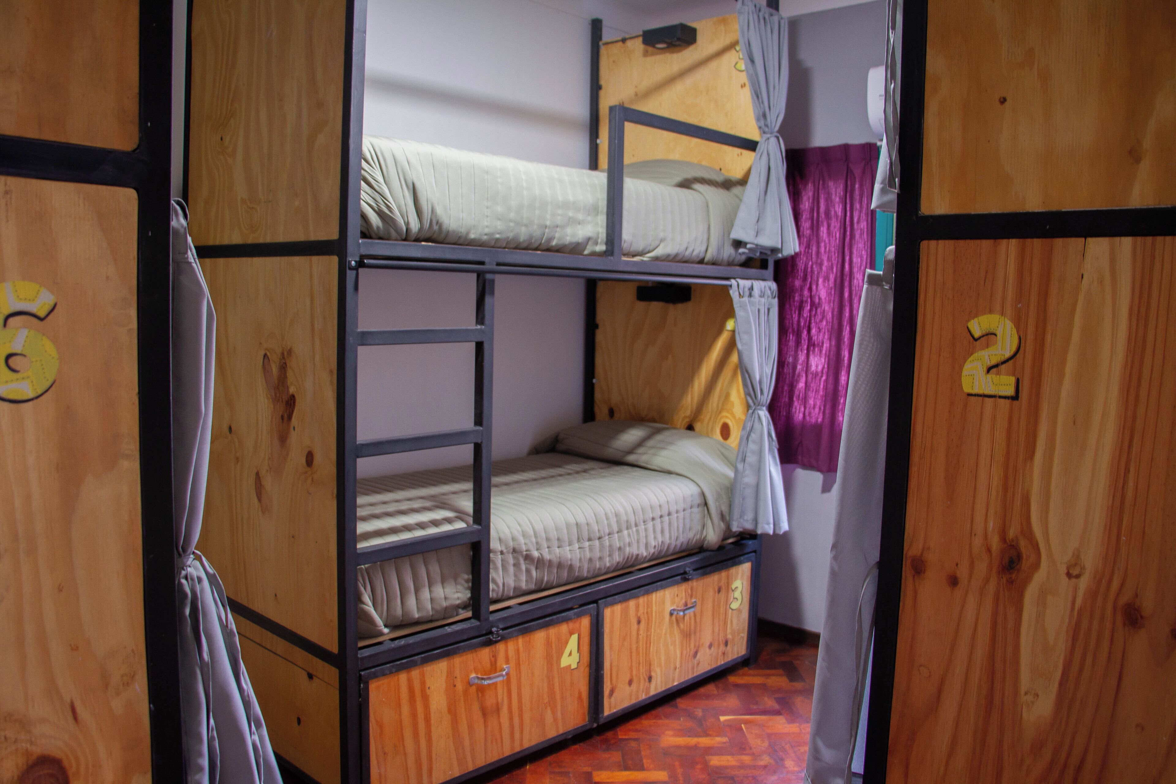Quarto com beliches, paredes de madeira e portas numeradas.