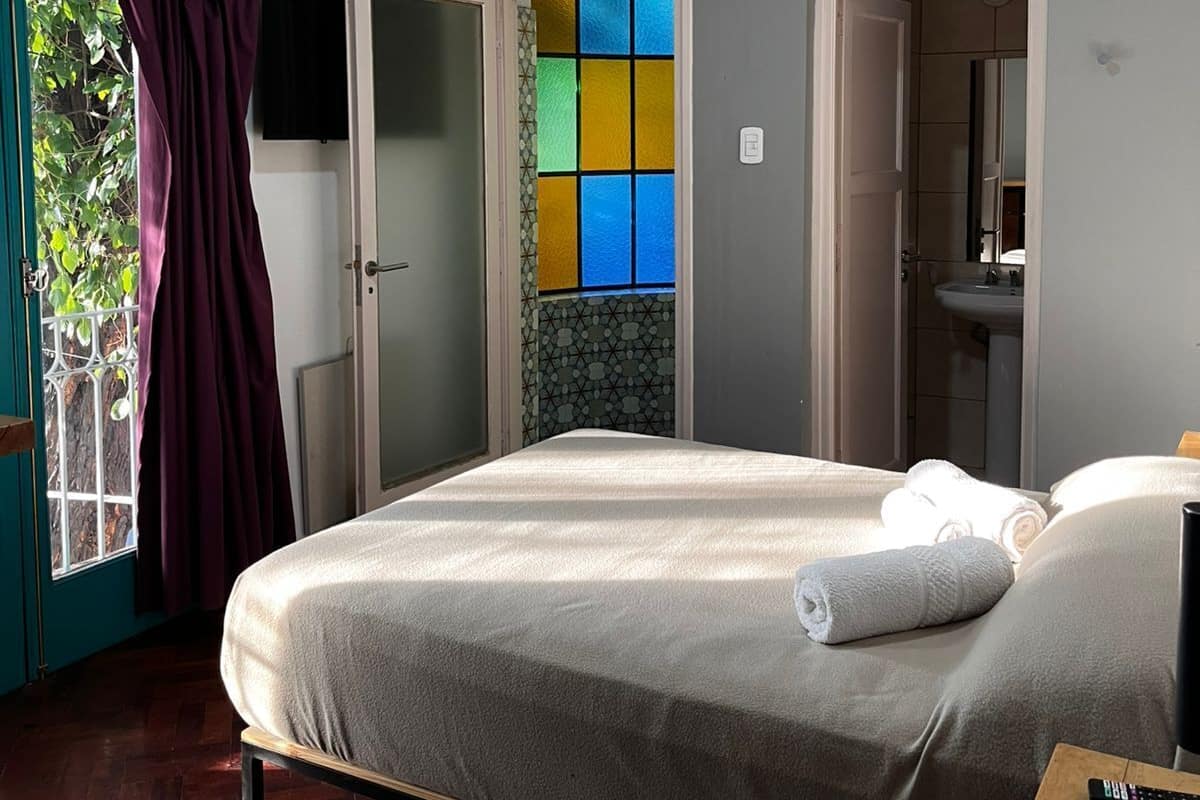 A hotel room with a bed, a TV, a bathroom, and a view of the outside.