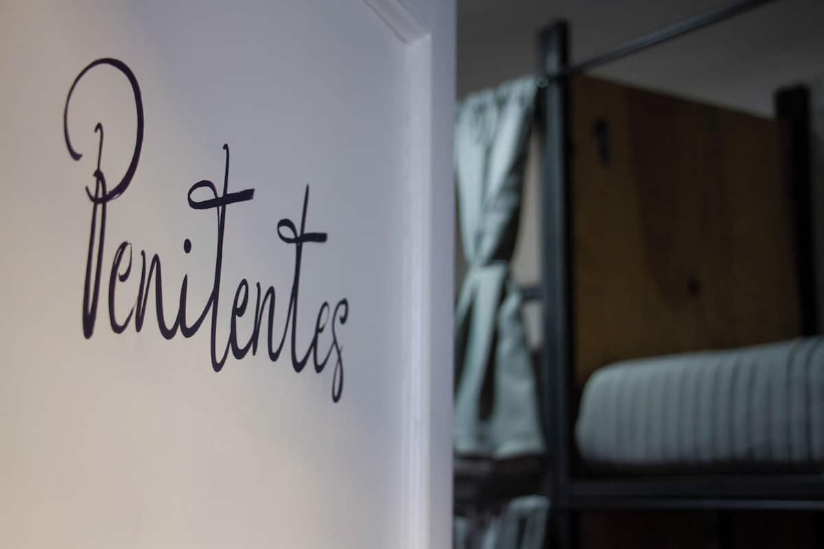 A room with a bed and a wall with the word "Penitentes" written on it.