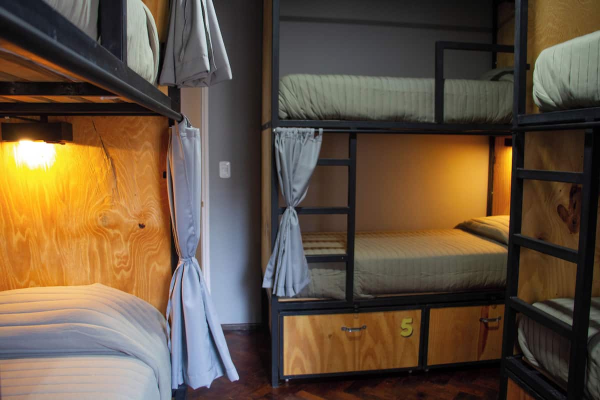 A room with bunk beds, wooden walls, and a warm light source.