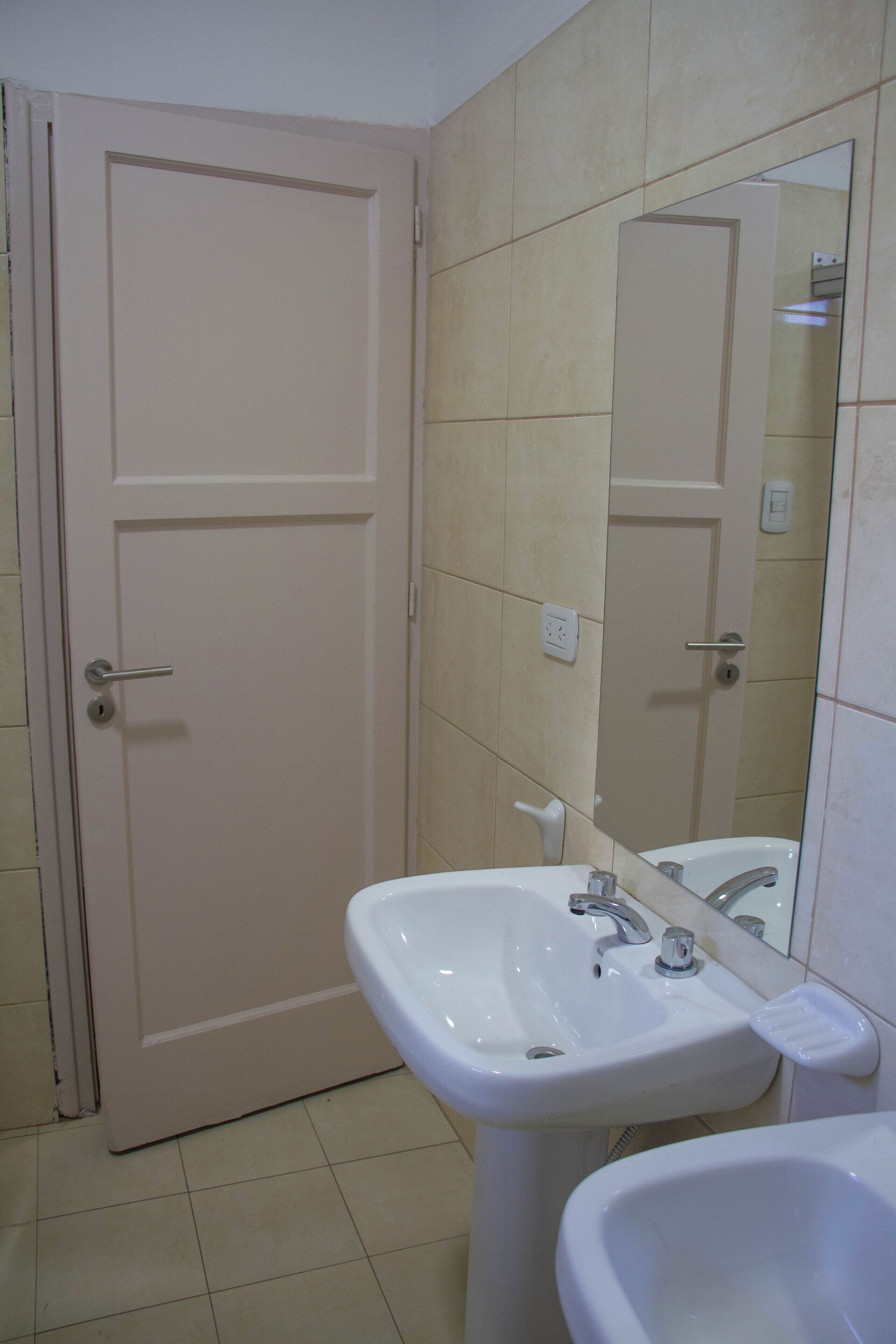 A bathroom with a white door, a sink with a mirror, and a bathtub.