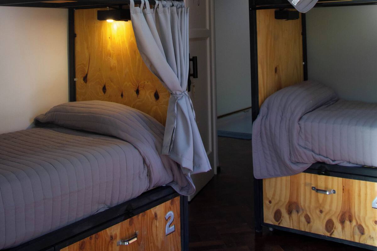 A bunk bed room with wooden headboards, curtains, and a small wooden cabinet with a drawer marked '2'.