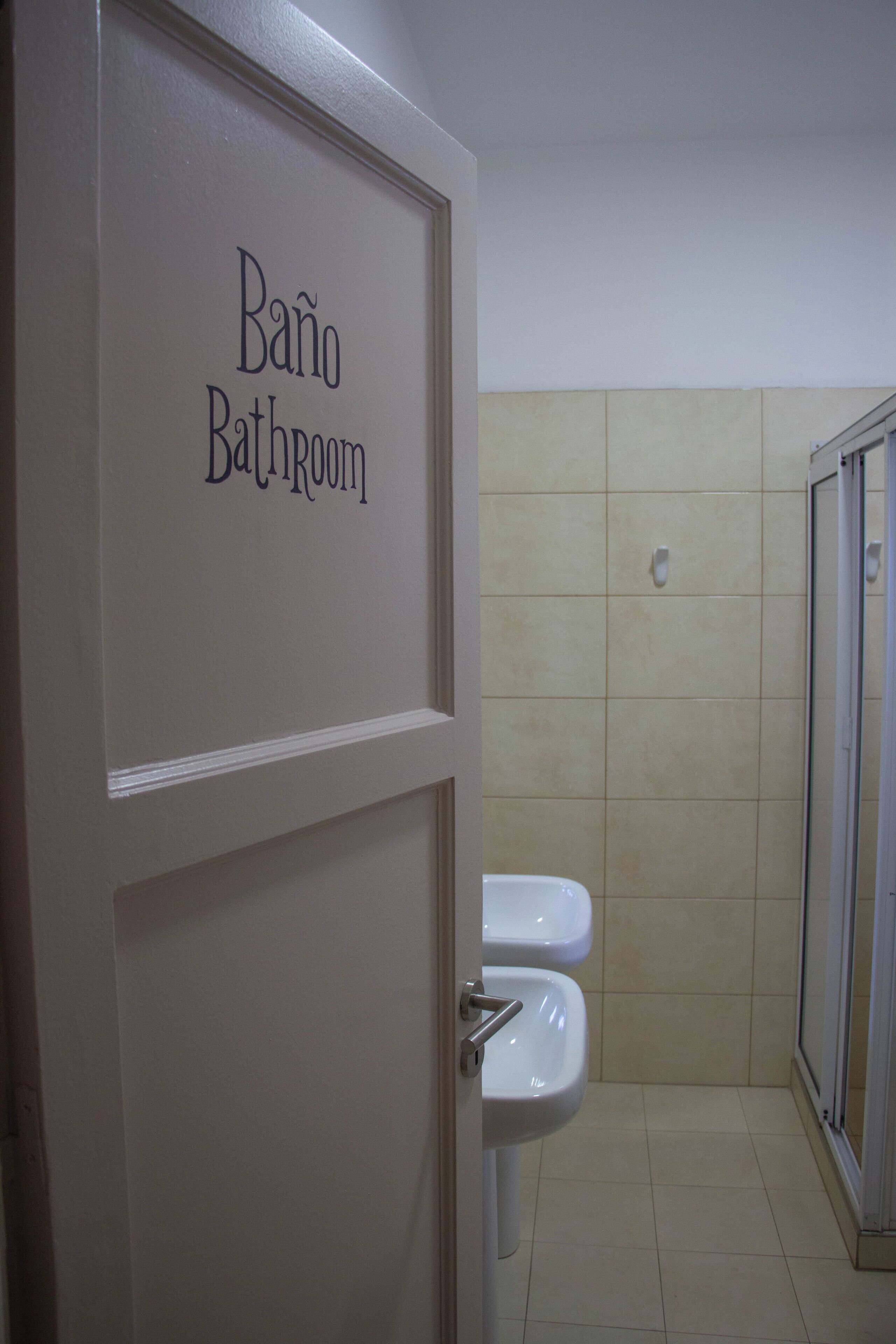 Un baño con un cartel que dice "Baño Bathroom" y una zona de ducha.
