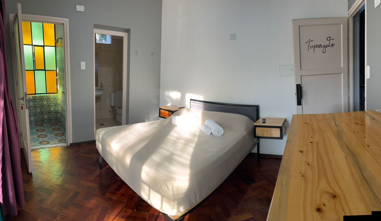 A bedroom with a bed, bedside table, and a wooden bench.