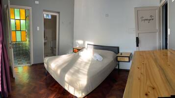 A bedroom with a bed, bedside table, and a wooden bench.
