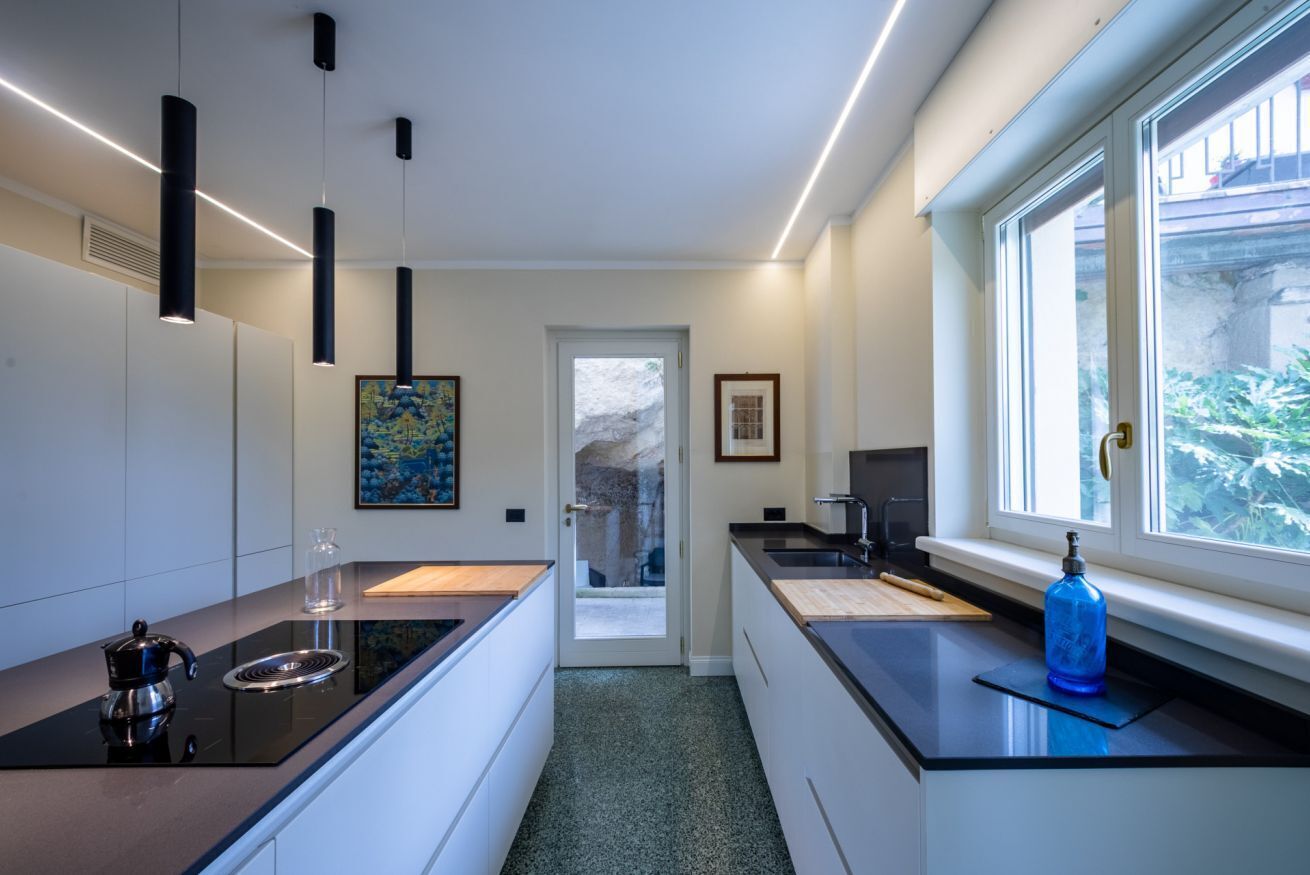 Una cocina moderna con encimeras negras, una cafetera y vistas a través de un ventanal.
