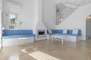 A modern living room with a blue sofa set, a white coffee table, and a staircase.