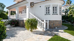 A two-story house with a white exterior, stone foundation, and a curved roof. - Casa Blanca | private pool - garden - bbq (Estepona)