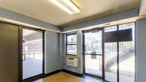 A hallway with a glass door, a window with a view of the outside, and a ceiling-mounted air conditioning unit.