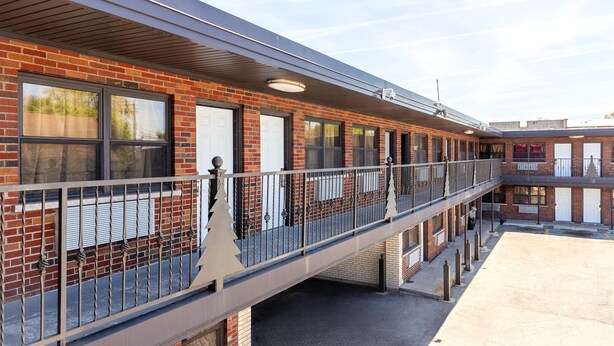 A multi-story building with a brick facade, multiple windows, and a covered walkway.