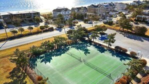 An aerial view of a residential area with a tennis court surrounded by houses and a road.
