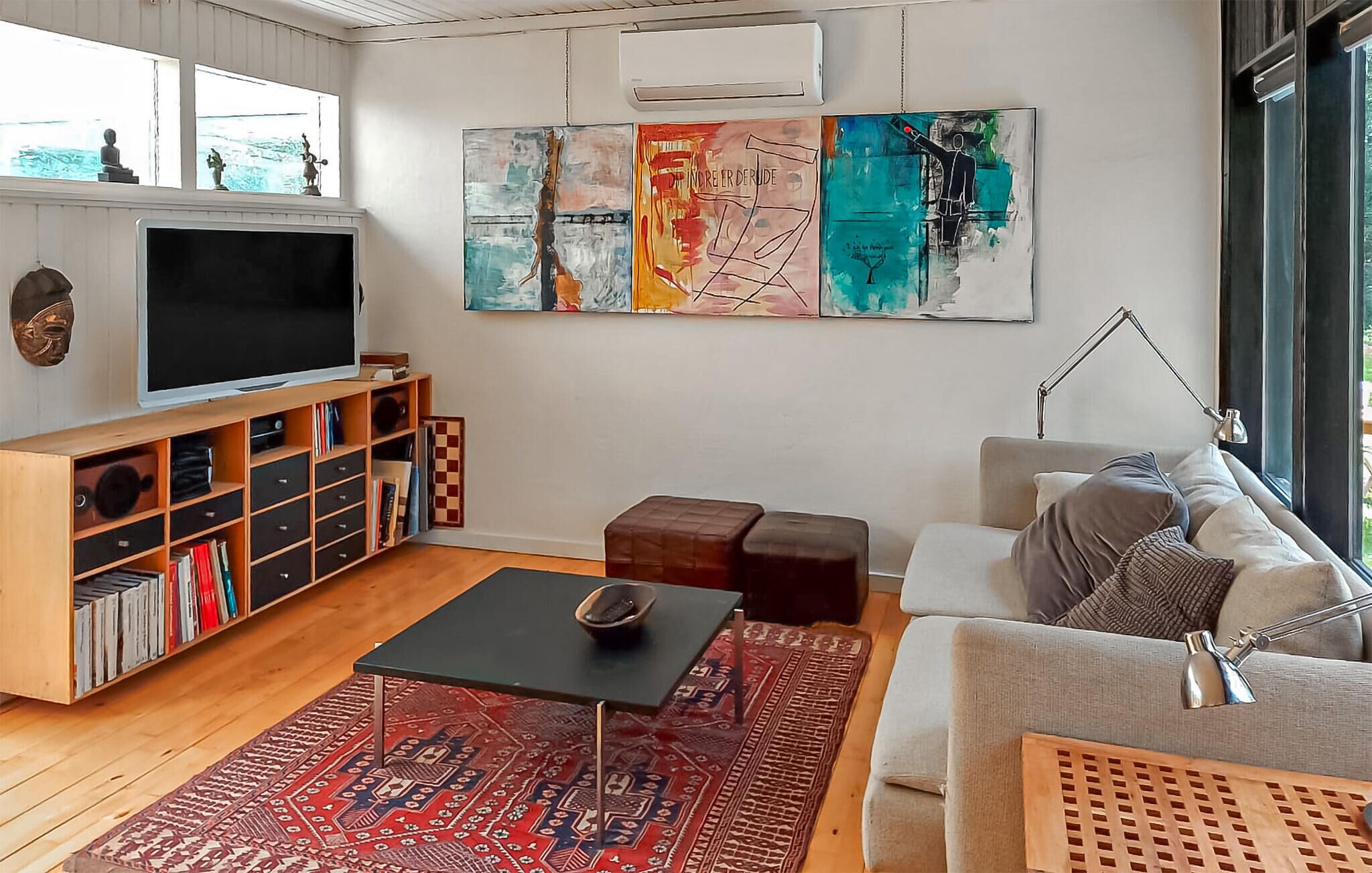 Un soggiorno moderno con una TV a schermo piatto, mensole in legno, un tavolino da caffè e un divano.
