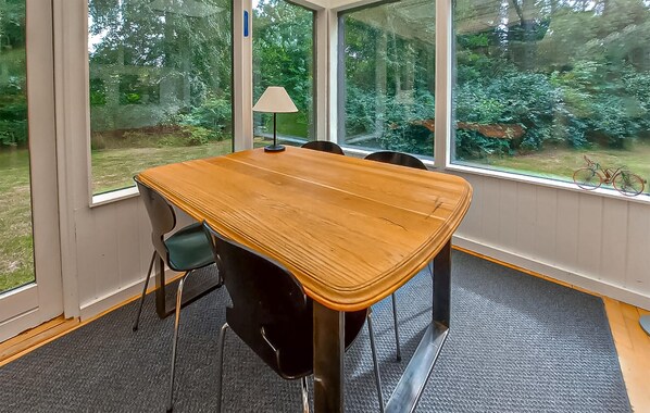 A room with a large window, a wooden table, and a lamp.