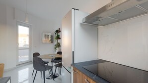 Eine moderne Küche mit schwarzem Arbeitsplatz, einem Edelstahl-Dunstabzug und einem Essbereich mit Tisch und Stühlen.
