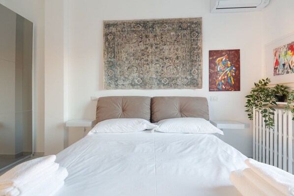 Ein Schlafzimmer mit einem Bett, einem großen Wandteppich und zwei Bildern an der Wand.