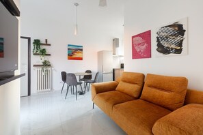 Ein modernes Wohnzimmer mit Sofa, Essbereich und Kunstwerken an den Wänden.