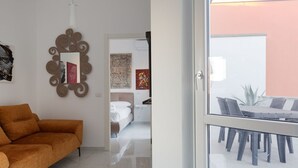 Ein modernes Wohnzimmer mit einer Couch, einem Spiegel und einem Essbereich mit Tisch und Stühlen.