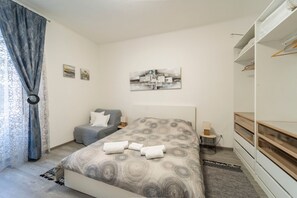 A bedroom with a bed, bedside tables, a wardrobe, and a painting on the wall.
