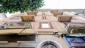 Un edificio de varios pisos con balcones, un escaparate visible con señalización y una vista despejada de la calle.