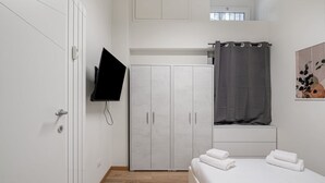 Ein Schlafzimmer mit Bett, Kleiderschrank, Fernseher und Duschvorhang.