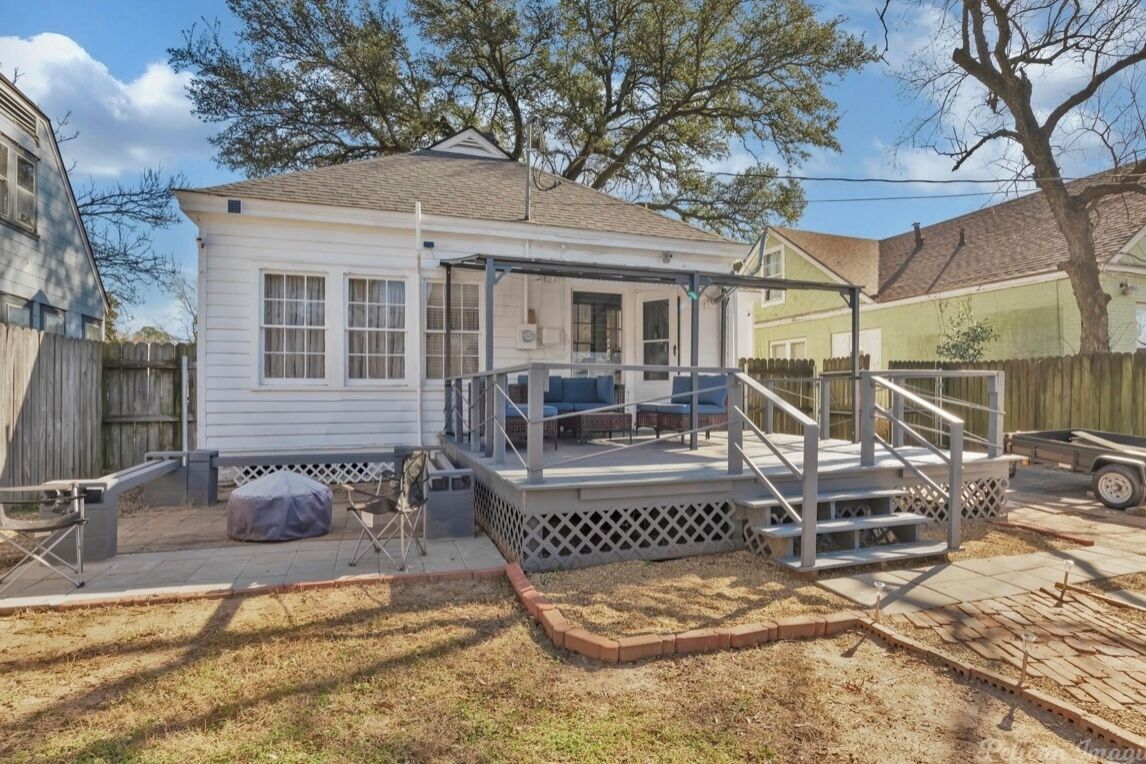 A single-story house with a covered porch, a fenced yard, and a wooden deck.