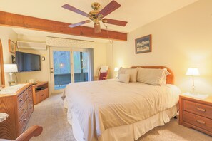 A bedroom with a bed, wooden headboard, bedside tables, a ceiling fan, a television, a desk, and a chair. - Official Seasons RMC Condo 08C - 2 Bedroom  - sleeps 8 - Dog Fees (Bartlett)