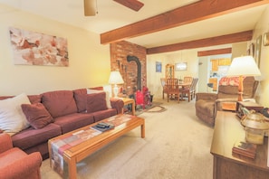 A living room with a sofa, coffee table, and a fireplace. There is a dining area with a table and chairs. - Official Seasons RMC Condo 08C - 2 Bedroom  - sleeps 8 - Dog Fees (Bartlett)