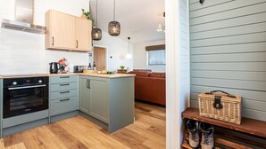 Una cocina moderna con armarios de madera, horno empotrado y lámparas colgantes.
