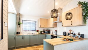 Una cocina moderna con armarios de madera clara, una isla central e iluminación colgante.