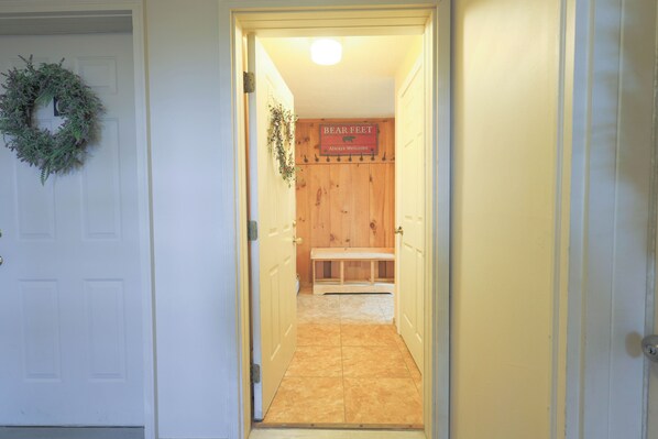 A hallway with a wooden bench, a sign reading 'Bear Feet,' and a door with a wreath. - Official Seasons RMC Condo 08D - 2 Bedroom - sleeps 7 - No Fees (Bartlett)