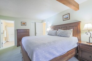 A bedroom with a wooden bed, a nightstand, a dresser, and a door leading to another room. - Official Seasons RMC Condo 08D - 2 Bedroom - sleeps 7 - No Fees (Bartlett)