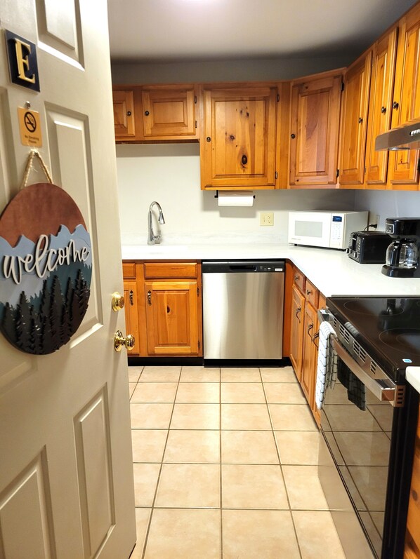 A kitchen with wooden cabinets, a dishwasher, a microwave, a toaster, and a coffee maker.