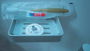 Un lavamanos con un cepillo de dientes y pasta de dientes en un recipiente de plástico.