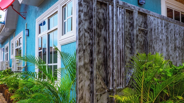 Un edificio con fachada azul, ventanas amplias y puerta de madera.