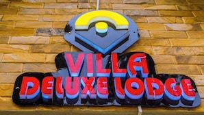 Un letrero para 'Villa Deluxel Lodge' con un logo estilizado encima del texto.