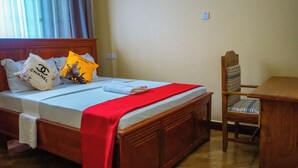 Una habitación de hotel con una cama de madera, una colcha roja y una silla con un cojín estampado.