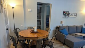 A dining area with a round wooden table and chairs, a sofa, and a lamp.