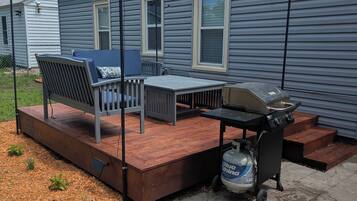 A patio with a grill, outdoor furniture, and a water dispenser.