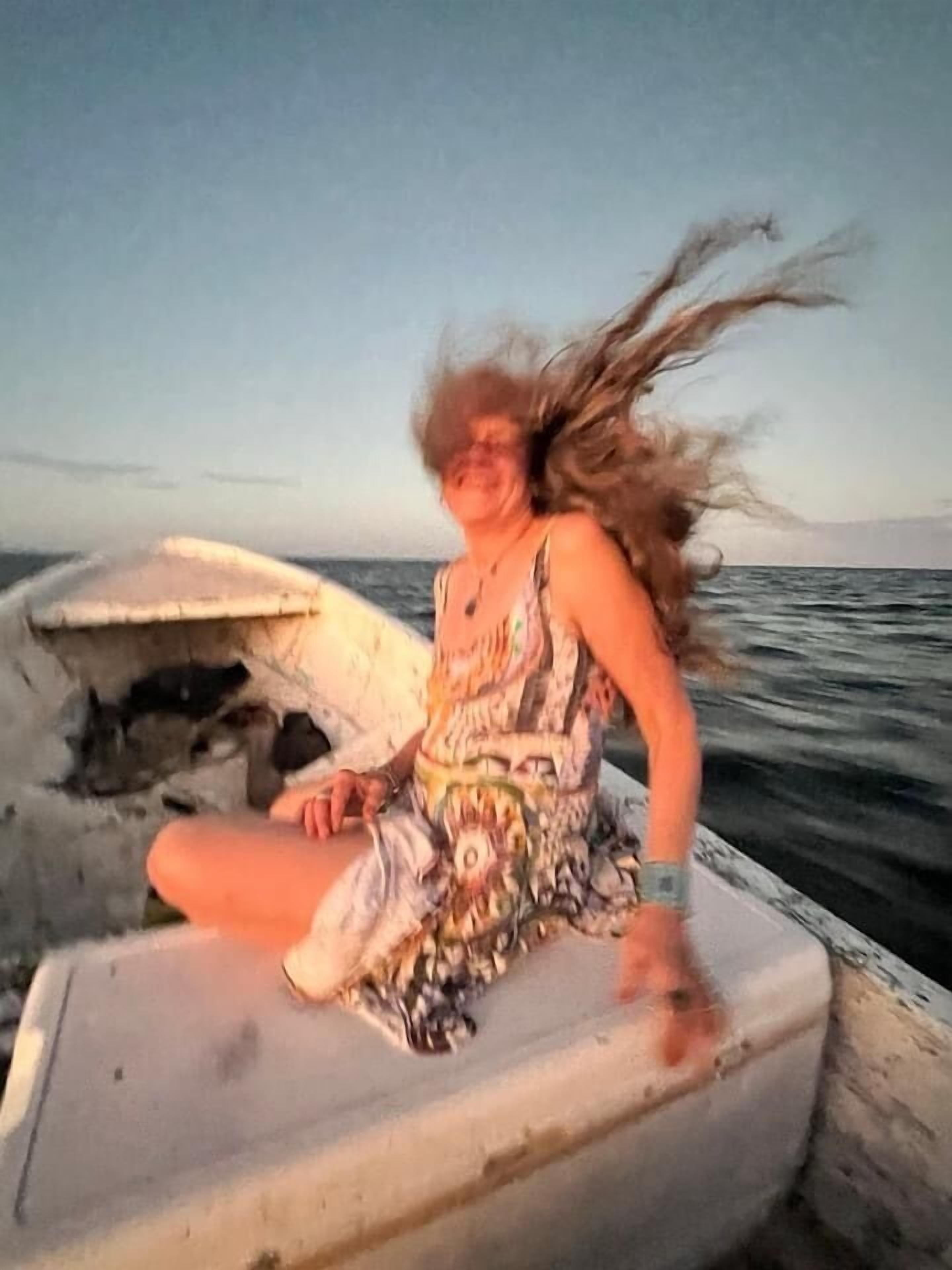 A person sitting on a boat with a damaged hull.