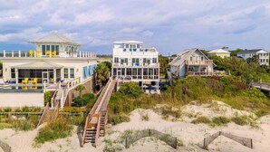 A beachfront property with multiple houses, a pool, and a wooden walkway leading to the beach.