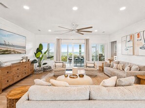 A spacious living room with a large sofa, a coffee table, and a television on the wall.