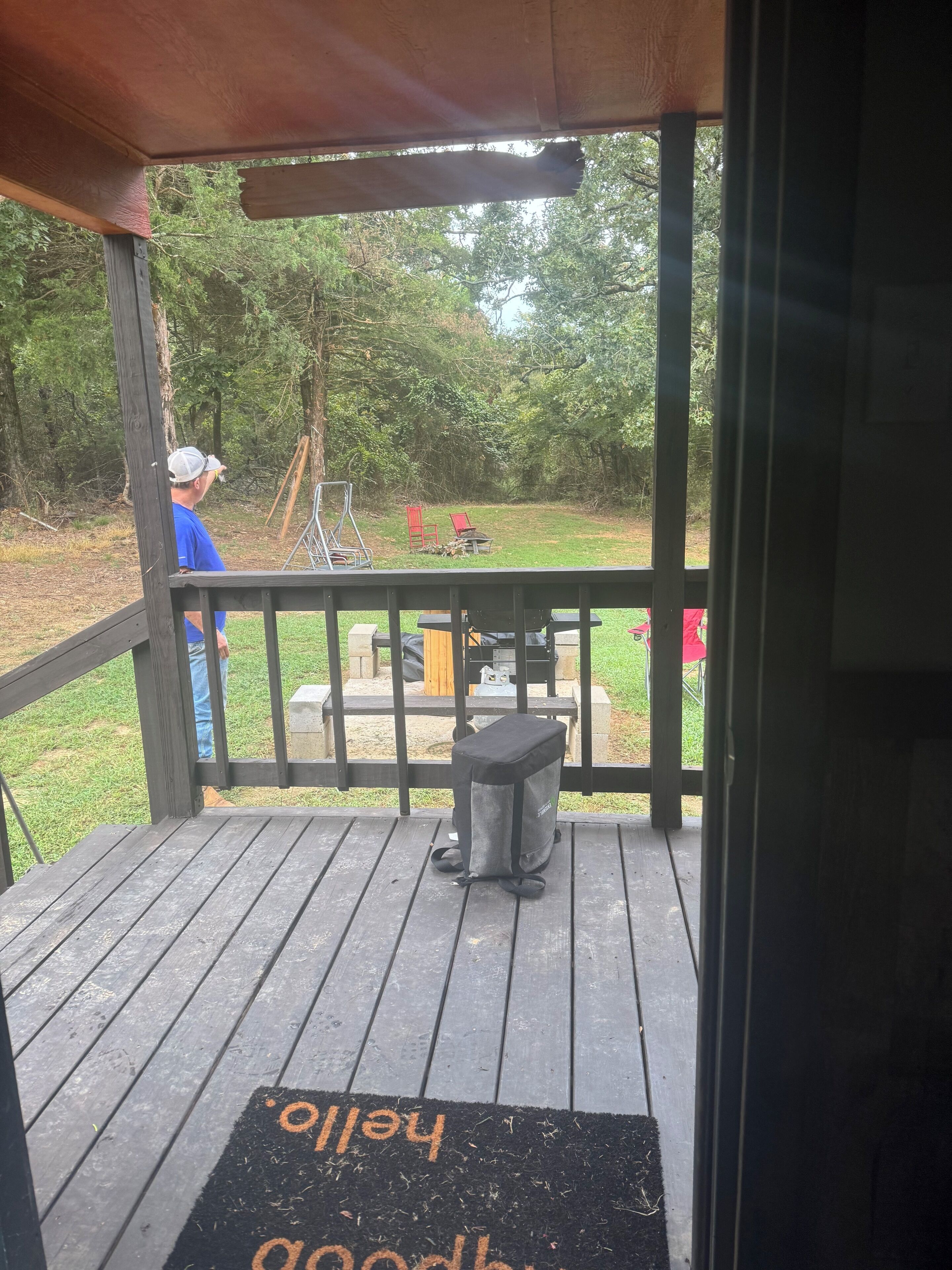 A wooden deck with a black mat reading "welcome home" and a metal grill.
