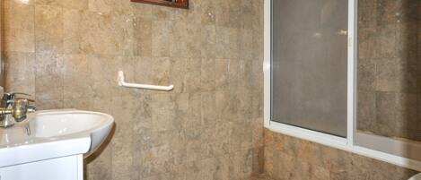 Une salle de bain comprenant un lavabo, des toilettes et un espace douche.