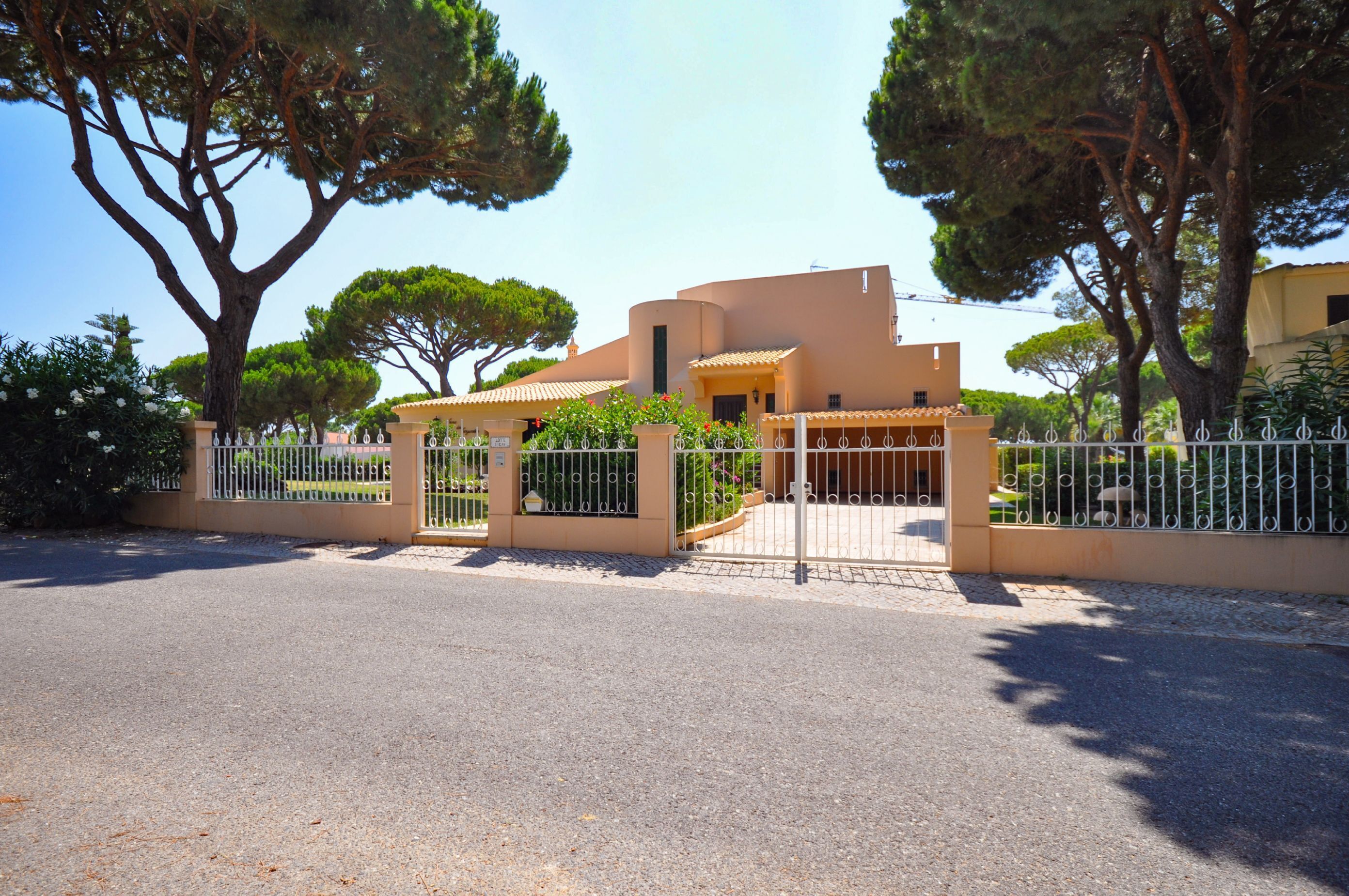 A gated entrance with a building featuring a curved roof and a small covered area with a railing.