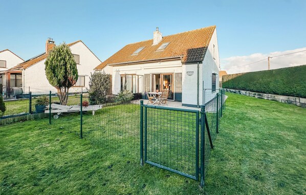 A residential property with a fenced backyard, a patio with outdoor furniture, and a house with a tiled roof. - 2 bedroom pet friendly home in Westende (Westende)