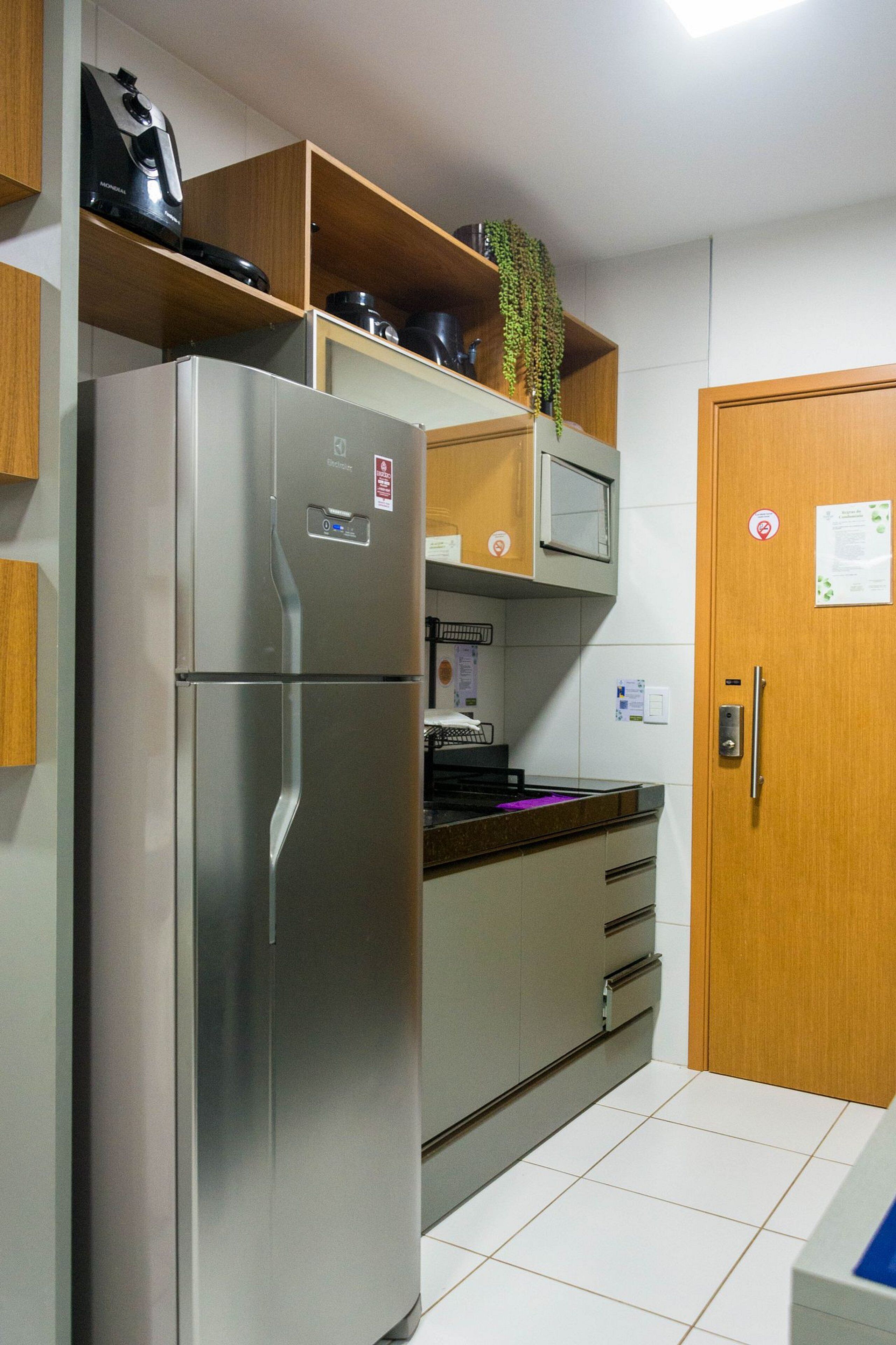 A kitchen with a stainless steel refrigerator, wooden cabinets, a microwave, and a sink.