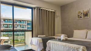 A modern hotel room with a large window, two beds, a sofa, and a small table. - Mana Beach Experience B 114 Muro Alto (Ipojuca)
