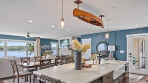 Una cocina moderna con una isla grande, armarios de madera e iluminación colgante.