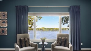 Una habitación con dos sillones, una mesita redonda y vistas a un lago.