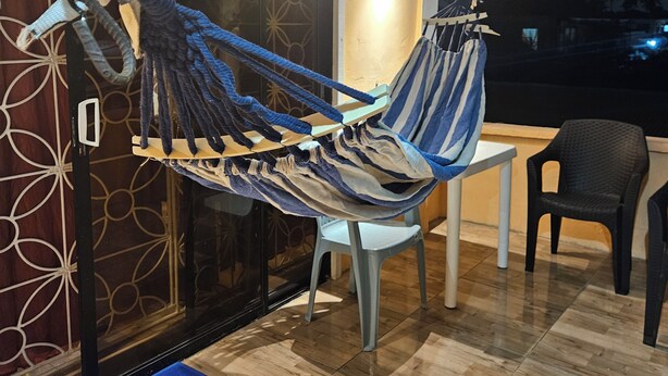 Un fauteuil suspendu dans une pièce dont le sol est carrelé, avec une petite table et une chaise.